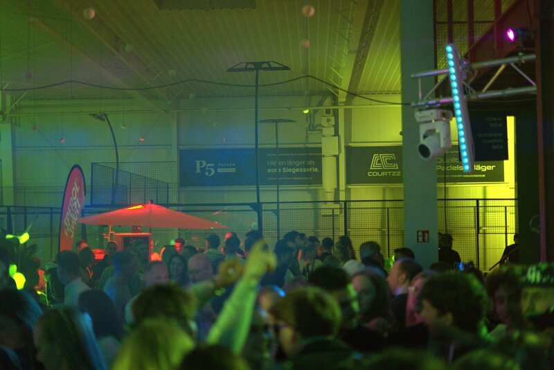 Volle Padelhalle in Neonlicht während der Charity-Party
