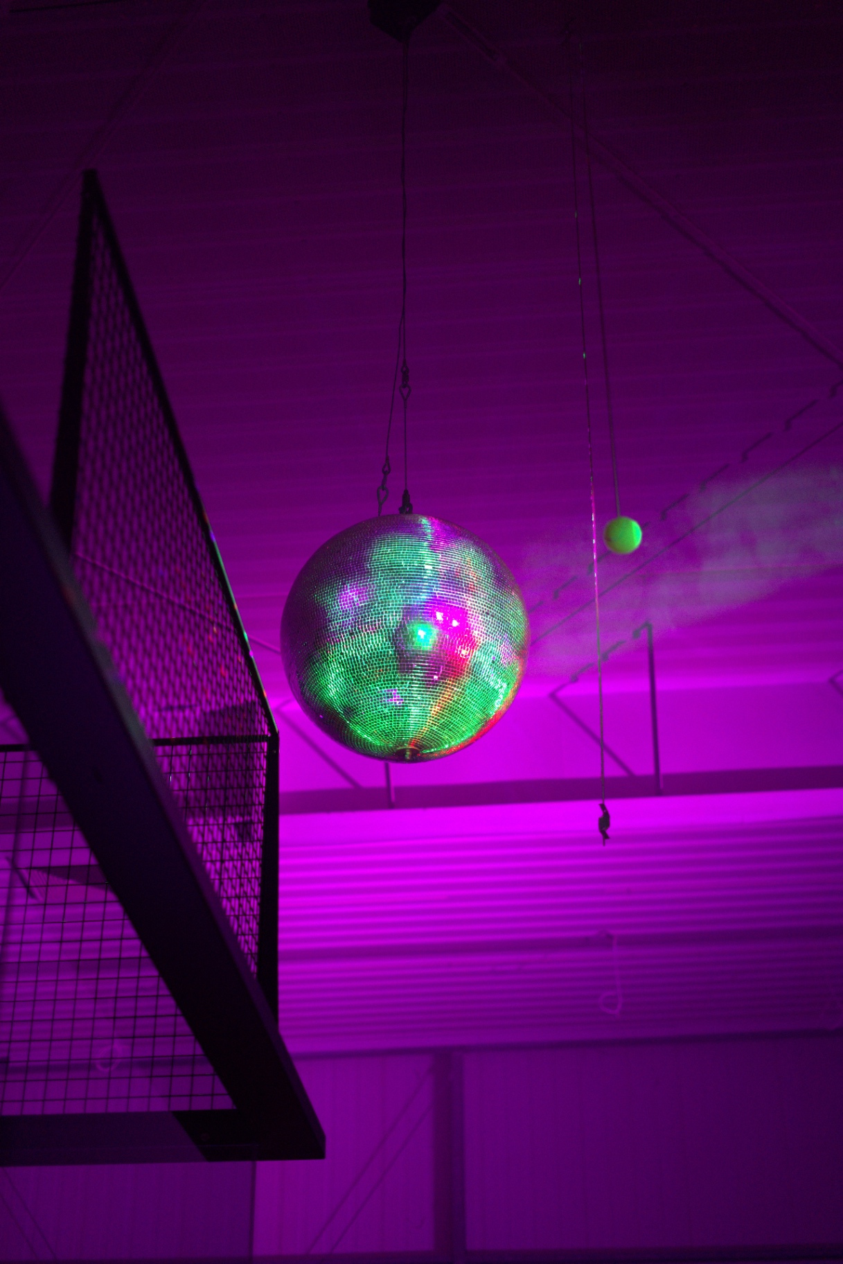 Discokugel über dem Padelcourt in pinkem Licht